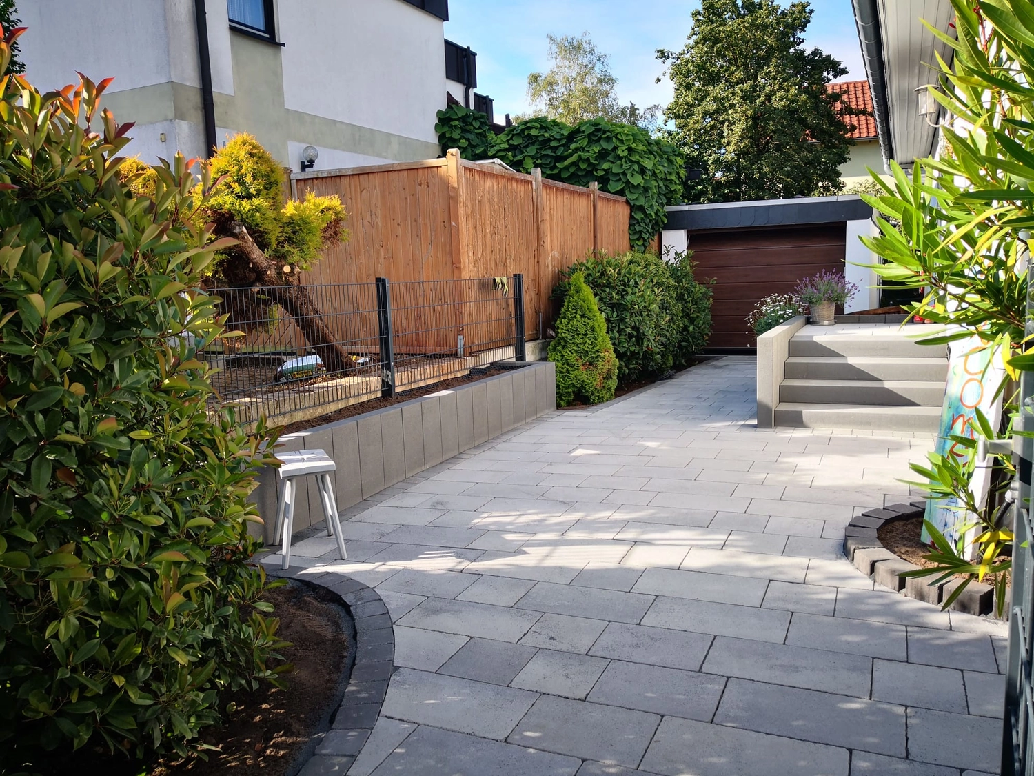 Zois Gartengestaltung – Dieser Hinterhof verfügt über moderne graue Pflastersteine ​​und eine elegante Stützmauer aus Stein.